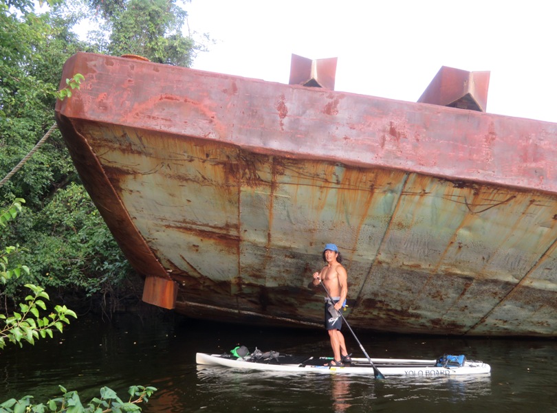 Me on SUP in front of the side of the barge lifted because it ran aground