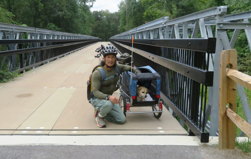 Daphne in carrier and me kneeling next to her and bicycle at bridge over Patuxent River